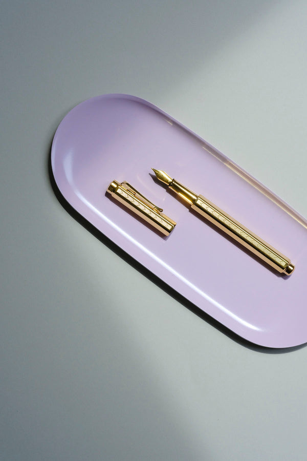 Caran d'Ache Ecridor Chevron fountain pen with an engraved barrel on a pink Lola stand.