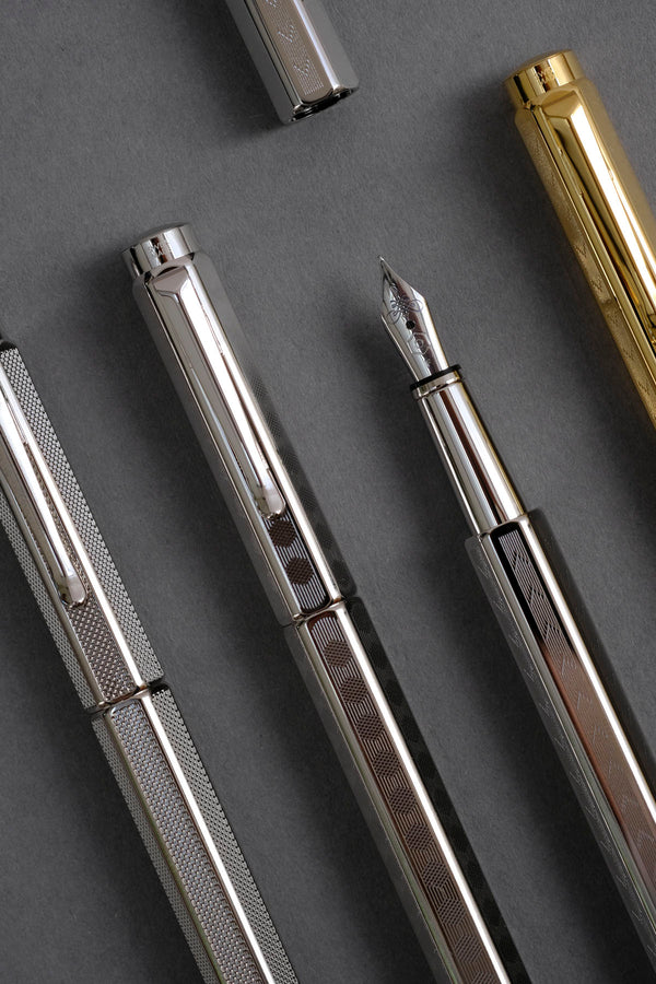 Caran d'Ache Ecridor Milanese Mesh, Chevron, and Heritage fountain pens on a gray background.
