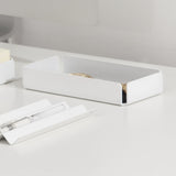 A white steel office accessories tray placed on a light-colored desk.