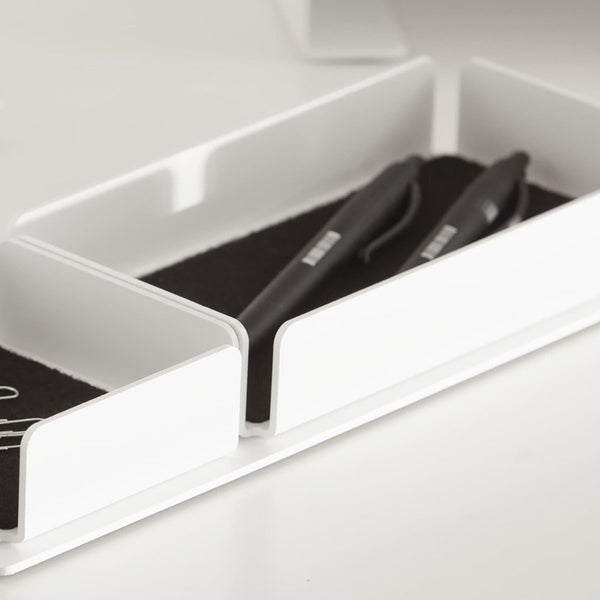 A white steel desk organizer set on a stand. The interior is finished with black felt, with pens and paper clips inside.
