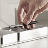 A white steel desk organizer set on a stand. The interior is finished with black felt.