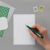 A sheet of Japanese cream-colored Tomoe River paper and a grid sheet that helps keep sentences aligned in straight lines.