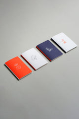 Pocket-sized notebooks from the Luna collection with a moon motif in orange, navy, and light grey.