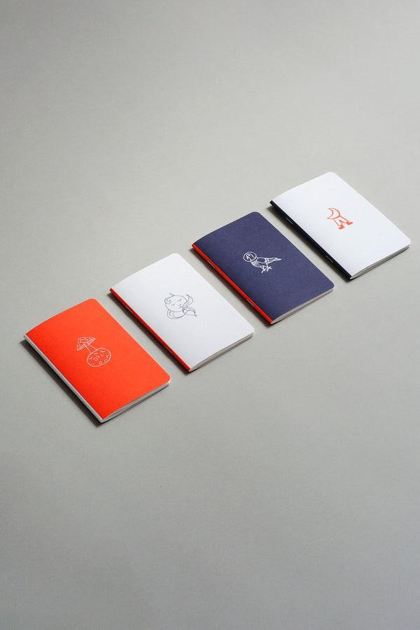 Pocket-sized notebooks from the Luna collection with a moon motif in orange, navy, and light grey.