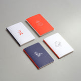 Pocket-sized notebooks from the Luna collection with a moon motif in orange, navy, and light grey, blank inside.