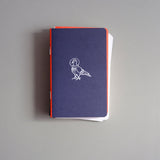 Pocket-sized softcover notebook with an illustration of an astronaut pigeon.
