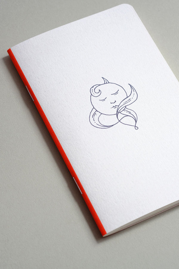 A small light grey notebook with a navy illustration inspired by the Moon.