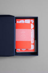 An open cardboard box containing a set of notebooks and stickers from the Luna collection.