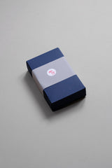 Navy blue paper box decorated with a semi-transparent band and a sticker.