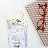 A cream-colored plastic paper clip holding receipts together.