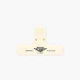 A cream plastic paper clip with a black logo featuring the Penco brand name.