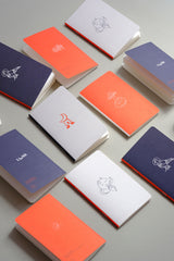 Pocket-sized notebooks from the Luna collection with a moon motif in orange, navy, and light grey.